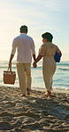 Couple, holding hands and walk with picnic basket at beach, smile and summer adventure with partner. Outdoor, happy people and travel with spouse on coastal vacation, love and marriage commitment