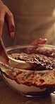 Mix, hands and women with cake batter in kitchen for baking, dessert or cupcakes in home. Stirring, wooden spoon and baker with person for teaching with chocolate mixture for sweet treat in house.