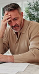Man, laptop and stress in home for finance, budget planning or asset management in kitchen. Mature person, anxiety or checking invoices with tech for financial expenses and paperwork in house