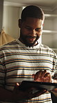 Travel, tablet or black man in house with plan, trip option or holiday selection on booking app. Happy, reading or male person in home with tech, vacation review or resort decision on tourism site.