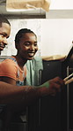 Couple, home and painting with help for renovation, conversation and smile with DIY project. Black man, woman and paintbrush for remodeling, house upgrade and happy with decor on kitchen cabinet
