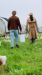 Agriculture, poultry and couple with bucket on farm for feeding, flock management or trade. Walk, back and people in agribusiness for egg collection, livestock monitoring or farmer industry in field
