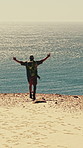 Backpacking, freedom and man at beach, drone and excited on coastal holiday, mockup space or travel. Ocean, celebration and person with backpack for adventure, hiking and back on vacation in nature