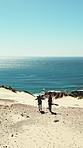Beach, freedom and men on dune, backpacking and celebration on coastal holiday, mockup space or trip. Ocean, drone and people with backpack, back and friends on hiking vacation or high five in nature