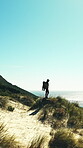 Beach, drone and man on hill, backpacking and sightseeing on coastal holiday, mockup space or travel. Ocean, scenery and person with backpack for adventure, hiking and explore on vacation in nature