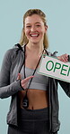 Face, fitness and open sign with personal trainer woman in studio for development or training. Funny, pointing and stop watch with happy coach on blue background for health or workout session