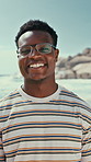Face, black man and smile at beach for travel, adventure and calm morning on summer holiday. Portrait, male person and happy at sea for fresh air, positive attitude and tropical vacation for me time