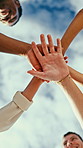 Team, below and hands together with cloudy sky for unity, trust or outdoor support in nature. Low angle, people or group of friends piling with stack for community mission, cohesion or solidarity