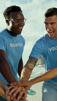 Volunteer, team or happy people with hands together on beach for community service or mission. Excited, group or cleaners piling with smile on ocean coast for cleaning, help or unity in solidarity