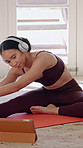 Yoga, woman and tablet with headphones for online class, stretching legs and fitness in living room. Female person, warm up and wellness in home with audio tech, video tutorial and how to exercise.