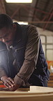 Carpenter, man and design in workshop with timber, pencil and problem solving for manufacturing. Black person, thinking and woodwork designer in factory with creative process, craft and production.