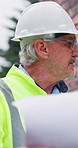 Architect, inspection and man with blueprint on construction site, walking and property development. Outdoor, civil engineering and mature person with floor plan, quality assurance and renovation