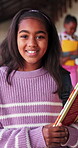 Smile, book and face of child in school hallway for education, knowledge and academy. Learning, literacy development and growth with student in corridor of campus for scholarship, project and study