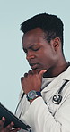 Serious, doctor and thinking in studio with tablet, consider research or medical history for diagnosis. Healthcare worker, black man and tech for problem solving, planning or idea on blue background.