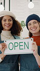 Hospitality, face and team in cafe with open sign, service notice and welcome to small business. Partnership, happy women and owners with billboard, ready and greeting display for restaurant startup
