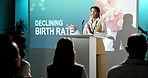 Presentation, podium and woman with speech for declining birth rate or economic pressure. Female person, speaker or discussion in seminar with microphone for global population shortage or pitch