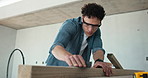 Carpenter, man and sanding in construction site with wood, building furniture or restoration project. Person, sandpaper and blow dust with smooth timber, craftsmanship skills and carpentry career.