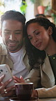 Couple, smile and relax with phone in coffee shop, conversation or reading post on social media app. Cafe, date and scroll blog on website, internet search and happy people with mobile and discussion
