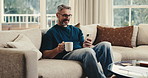 Happy, man and coffee in home with phone, reading morning news and online entertainment on weekend. Mature person, smile and relax in living room with tech, warm drink or mobile app for social media.