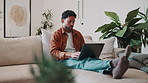 Break, typing and man with laptop on couch for social media, reading blog and streaming service. Networking, email and search with male person in living room of home for website, sign up and relax