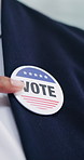 Hands, person and political badge for vote, election day and participation for equality awareness. Candidate, point or button in office for voting rights, local responsibility and democratic campaign