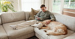 Tablet, support and man with dog on sofa in home for research on pet adoption, foster care or wellness. Relax, digital technology and person reading blog on app for animal health in house with puppy.