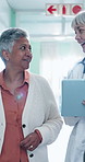 Tablet, doctor and senior patient in hospital lobby together with online records, connection and app. Healthcare, technology and happy women walking for discussion, discharge and medical stay review