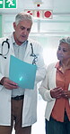 Folder, doctor and senior patient in hospital lobby together with application form, results and plan. Healthcare, paperwork and man walking with woman for discussion, discharge and medical advice