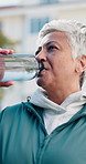 Fitness, drink and senior woman in city for rest, workout recovery and hydration with bottle. Exercise break, active retirement and old person with water for health, beverage and thirsty with runner