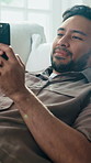 Relax, phone and happy man on sofa for thinking, social media forum or online dating on weekend. Mobile, smile and person in home lounge with chat app, response idea and communication with match
