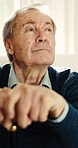 Thinking, cane and senior man in home for reflection, nostalgia and memory in retirement. House, thoughtful and elderly person with walking stick for balance, support and wellness for assisted living