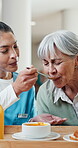 Healthcare, caregiver and feeding old woman for homecare, meal assistance and food for nutrition. Helping, carer and senior with soup for healthy eating, assisted living or compassion in care routine