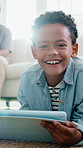 Tablet, relax and face of child in home for watching movie, series or film in living room on weekend. Happy, digital technology and portrait of boy kid on floor for streaming show on app subscription