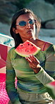 Picnic, smile and woman with watermelon on beach for summer vacation, getaway or weekend trip. Happy, sunglasses and person eating fruit for healthy snack by ocean for holiday, relax or travel.
