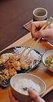Chinese food, chopsticks and hands of person in restaurant for dining, hospitality or meal. Cuisine, dish and eating with customer in traditional eatery for culture experience, delicacy or hunger