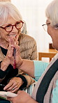 Home, happy and old women with book, high five or problem solving success for word search on weekend. Senior friends, smile and talk in house with sudoku puzzle, connection or support for retirement.