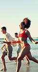 Fun, sunset and friends at beach with running, good time or happy moment on summer holiday. Wave splash, space or people at ocean with playful energy, group bonding or get together on getaway evening