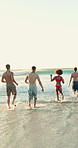 Holiday, back and friends at beach with running, good time or fun moment on summer break. Space, waves or people at ocean with playful energy, group bonding or get together on outdoor getaway.