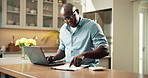 Laptop, home and black man with finance for mortgage expenses, bills or budget planning in kitchen. Male person, documents or checking invoice with computer for financial assessment or tax in house