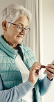 Happy, old woman and texting with phone in home, chat or communication with contact on social media. Typing, message and senior person with mobile, retirement and internet search with tech in house