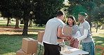 Charity, volunteer team and boxes in park for support, community service or food donation for relief. Collaboration, NGO and people for help, aid package and grocery distribution in nonprofit