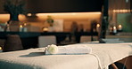 Calm, flower and towel in empty spa, comfort and bokeh with ambience at luxury hotel for decor. Floral, resort and soft folded fabric for wellness, aromatherapy and hospitality with massage table