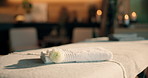Peace, flower and towel in empty spa, comfort and bokeh with ambience at luxury hotel for decor. Floral, resort and soft folded fabric for wellness, aromatherapy and hospitality with massage table