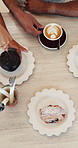 Above, hands and friends at cafe with dessert, pastries and relax together with morning food. Customers, drink or people with breakfast at coffee shop, chocolate muffin or eating treats with top view