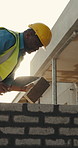 Bricklayer, black man and building with tool for construction, boundary wall or property extension. Worker, mature block mason or trowel on site for remodeling, manual labor or mortar for bricklaying