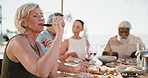 Woman, friends and drinking wine on patio with lunch, relax and bonding together in summer holiday. Mature people, chill and alcohol beverage outdoor in backyard with food, gathering and vacation.