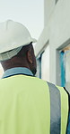 Engineer, inspection or man at construction site with helmet, property evaluation or quality control. Back, supervisor and person outdoor with PPE for building assessment, infrastructure and safety.