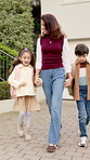 Walking, neighborhood and mom holding hands with children outdoor for trip, journey and travel. Family, suburbs and happy mother with kids for bonding, connection and morning commute to school