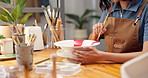 Woman, hands and painting in workshop with ceramic bowl, diy hobby or learning for skill development. Artist, person and creativity in art studio with paintbrush, craft tools and color for project.