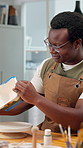 Smile, black man and painting in workshop for pottery, course and custom design of handmade craft. Person, admiration and decoration in class with clay bowl, artistic process and porcelain creation
